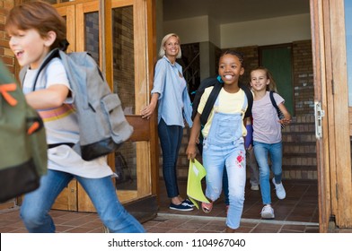 Group of elementary school children running outside at the end of the lessons. Happy school boys and girls running outside from school building. Finish school and summer vacation concept. - Shutterstock ID 1104967040