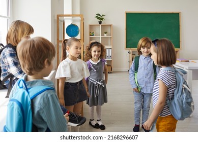 Group of elementary school children standing in the classroom and talking. Bunch of cute kids communicating with each other. Happy little boys and girls meet and make friends at school