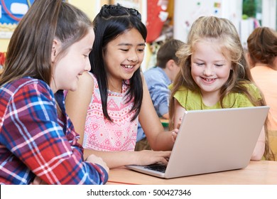 Group Of Elementary School Children Working Together In Computer Class