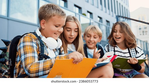 Group of elementary school children writing in their copybooks having an outdoor classwhile sitting on stairs of modern school building background. - Powered by Shutterstock