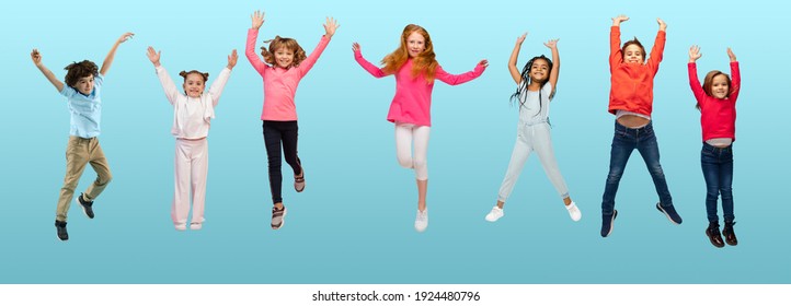 Group of elementary school kids or pupils jumping in colorful casual clothes on blue studio background. Creative collage. Back to school, education, childhood concept. Cheerful girls and boys.