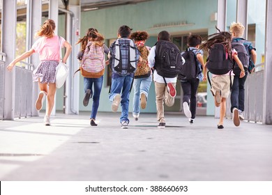 Group of elementary school kids running at school, back view