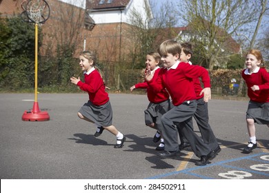 Group Of Elementary School Pupils Running In Playground