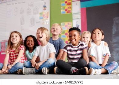 Group Of Elementary School Pupils Sitting On Floor In Classroom