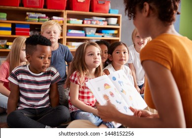 Group Of Elementary School Pupils Sitting On Floor Listening To Female Teacher Read Story - Powered by Shutterstock