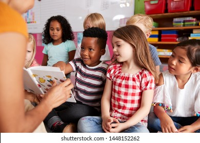 Group Of Elementary School Pupils Sitting On Floor Listening To Female Teacher Read Story - Shutterstock ID 1448152262
