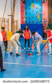Group of elementary school students playing floorball together in a gym class, promoting teamwork, coordination, and physical activity