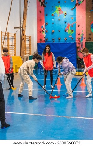 Group of elementary school students playing floorball together in a gym class, promoting teamwork, coordination, and physical activity