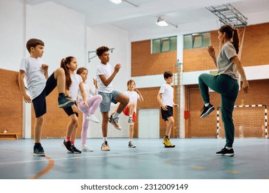 Group of elementary students having PE class with their sports teacher at school gym. - Powered by Shutterstock