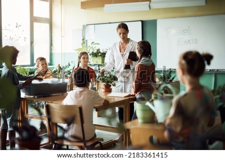 Group of elementary students learning about plants with their teacher during botany class at school. 