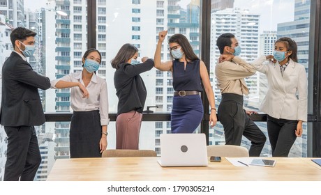 Group Of Employees In An Office Wearing A Mask  Prevention Covid 19disease  And Greeting Each Other, Using Elbows To Collide In The Meeting Room.New Normal And Social Distancing Concept.