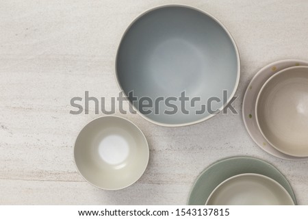 Group of empty blank ceramic round bowls and plates on white stone blackground, Top view of traditional handcrafted kitchenware concept