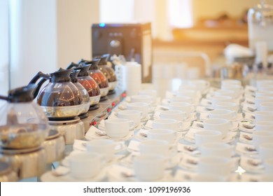 Group of empty Many rows of white ceramic coffee or tea cups and spoons on glass table, in break seminar event.