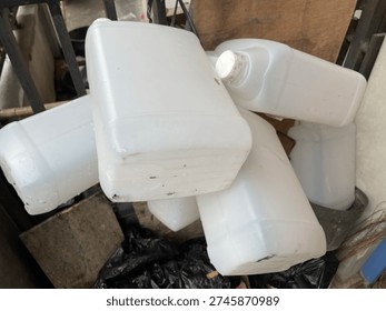 Grupo de bidones de plástico blanco vacíos y botes amontonados en un entorno al aire libre.