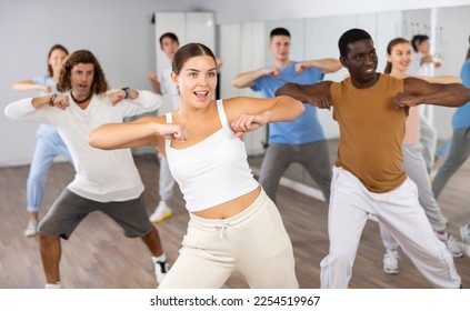 Group of energetic different people learning dance at dance class - Powered by Shutterstock