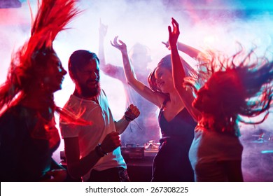 Group Of Energetic Friends Dancing In Night Club