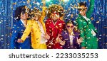 Group of energetic funny friends who are having fun and dancing together in confetti at disco party. Young people in colorful suits laugh out loud against backdrop of shiny foil curtain. Banner.