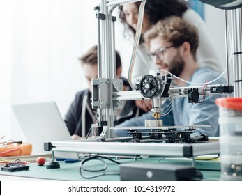 Group of engineering students using a 3D printer and a laptop in the lab, technology and learning concept