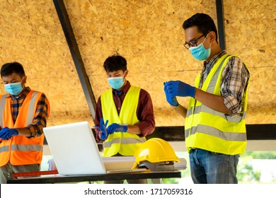 Group Of Engineering Team Wear Protective Face Masks Safety For Coronavirus Disease 2019 (COVID-19) Meeting To Plan For New Project  Measuring Layout Of Building Blueprints In Construction Site.