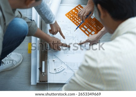 Group of engineers and architects collaborating on building blueprint with technical drawing tools during project planning stage.