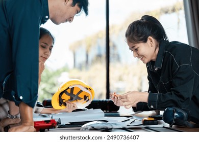 Group of Engineers Collaborating on a Project in a Modern Office Environment with Safety Gear and Blueprints