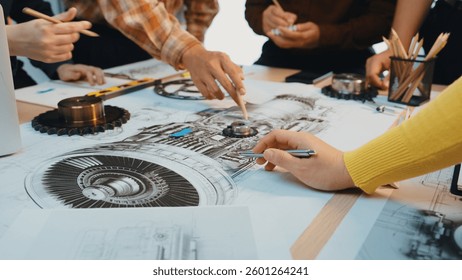 A group of engineers engaged in a creative workshop, actively analyzing detailed technical drawings related to machinery and mechanical components with various tools. SACTR