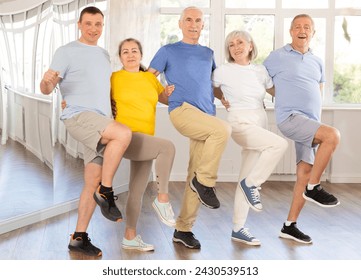 Group of enthusiastic cheerful mature men and women traditionally lined in row while performing Greek sirtaki during dance class in sunny studio - Powered by Shutterstock