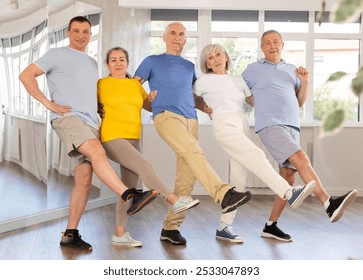 Group of enthusiastic cheerful mature men and women traditionally lined in row while performing Greek sirtaki during dance class in sunny studio - Powered by Shutterstock