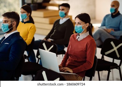 Group Of Entrepreneurs With Protective Face Masks Attending A Seminar In Board Room. Focus Is On Businesswoman Using Laptop. 