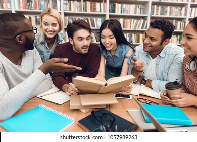 Group Of Ethnic Multicultural Students Discussing Studying Sitting At Table In Library.