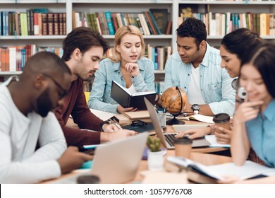 Group Of Ethnic Multicultural Students In Sitting At Table Library. Students Are Talking And Reading.