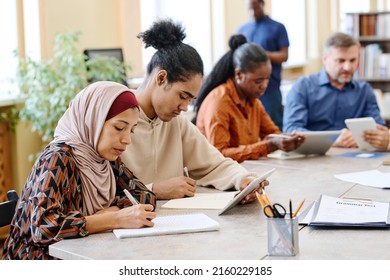 Group of ethnically diverse people having language lesson for immigrants sitting at table doing task with use of digital tablets - Shutterstock ID 2160229185