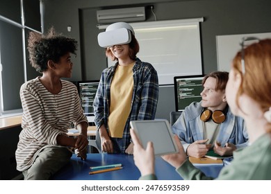 Group of ethnically diverse teen students working together on software for VR headset with use of digital tablet - Powered by Shutterstock