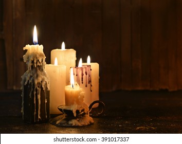 Group of evil candles burning in the darkness and copy space on wooden background. Black magic ritual or scary halloween rite. 