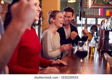 Group Of Excited Customers In Sports Bar Watching Sporting Event On Television