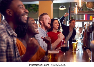 Group Of Excited Customers In Sports Bar Watching Sporting Event On Television