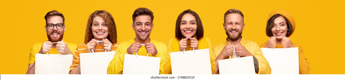 Group Of Excited Diverse People With Blank Shopping Bags Smiling And Looking At Camera Against Yellow Background