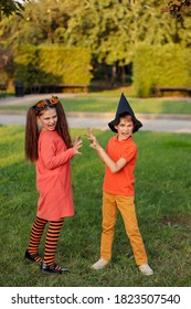 Group Of Excited Kids In Costumes Smiling And Running On The Lawn Celebrating Halloween In The Park