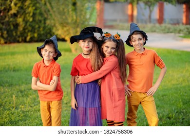 Group Of Excited Kids In Costumes Smiling And Running On The Lawn Celebrating Halloween In The Park