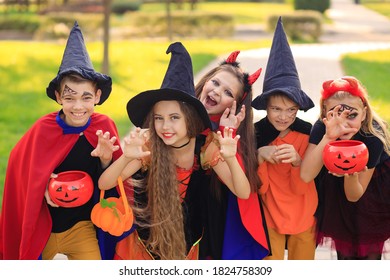 Group Of Excited Kids In Costumes Smiling And Running On The Lawn Celebrating Halloween In The Park