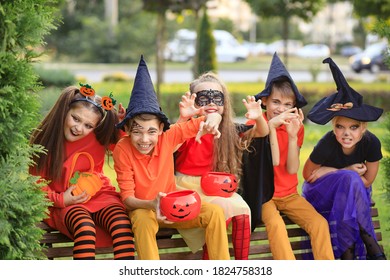 Group Of Excited Kids In Costumes Smiling And Running On The Lawn Celebrating Halloween In The Park