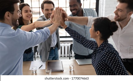 Group of excited multi-ethnic office staff members stack palms together express unity, giving high five gesture sharing department success, sales increase, career growth, team building spirit concept