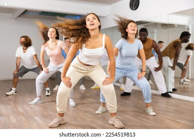 Group of excited young adult diverse dancers performing dynamic movements during training together in fitness studio - Powered by Shutterstock