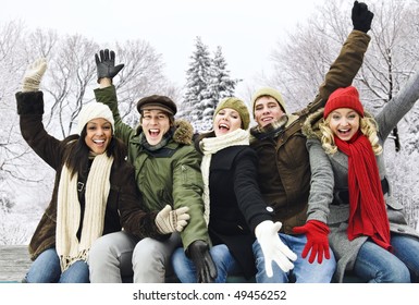 Group Of Excited Young Friends With Arms Raised Outdoors In Winter