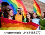 Group of excited young friends enjoying together on gay pride day. Joyful people gathered from LGBT community hugging laughing outdoors. Generation z and open minded. 
