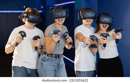 Group of excited young friends with gaming controllers in hands and VR goggles having fun in virtual reality room. Concept of modern immersive interactive experience.. - Powered by Shutterstock