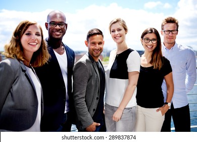 Group Of Executives Smiling And Posing Outside For Picture.