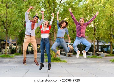 Group of exuberant young friends cheering and leaping in the air with arms raised in celebration outdoors in a park - Shutterstock ID 2069849720