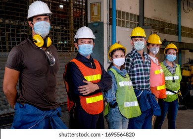 Gruppe von Arbeitern oder Technikern mit Maske Stand und sehen Sie rechts und bleiben Sie im Fabrikbereich.