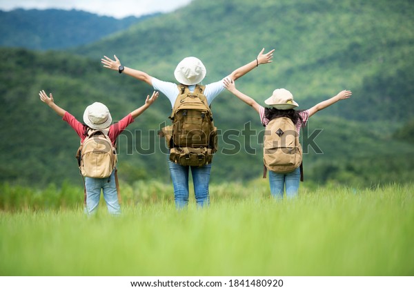 Group family children travel nature trips raise arms and\
standing see mountain outdoors, adventure and tourism for\
destination leisure trips for education and relax in nature park.\
Travel vacations 